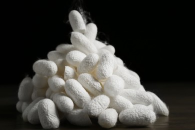Photo of Heap of white silk cocoons on wooden table, closeup