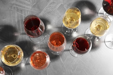 Different glasses with wine on grey background, flat lay