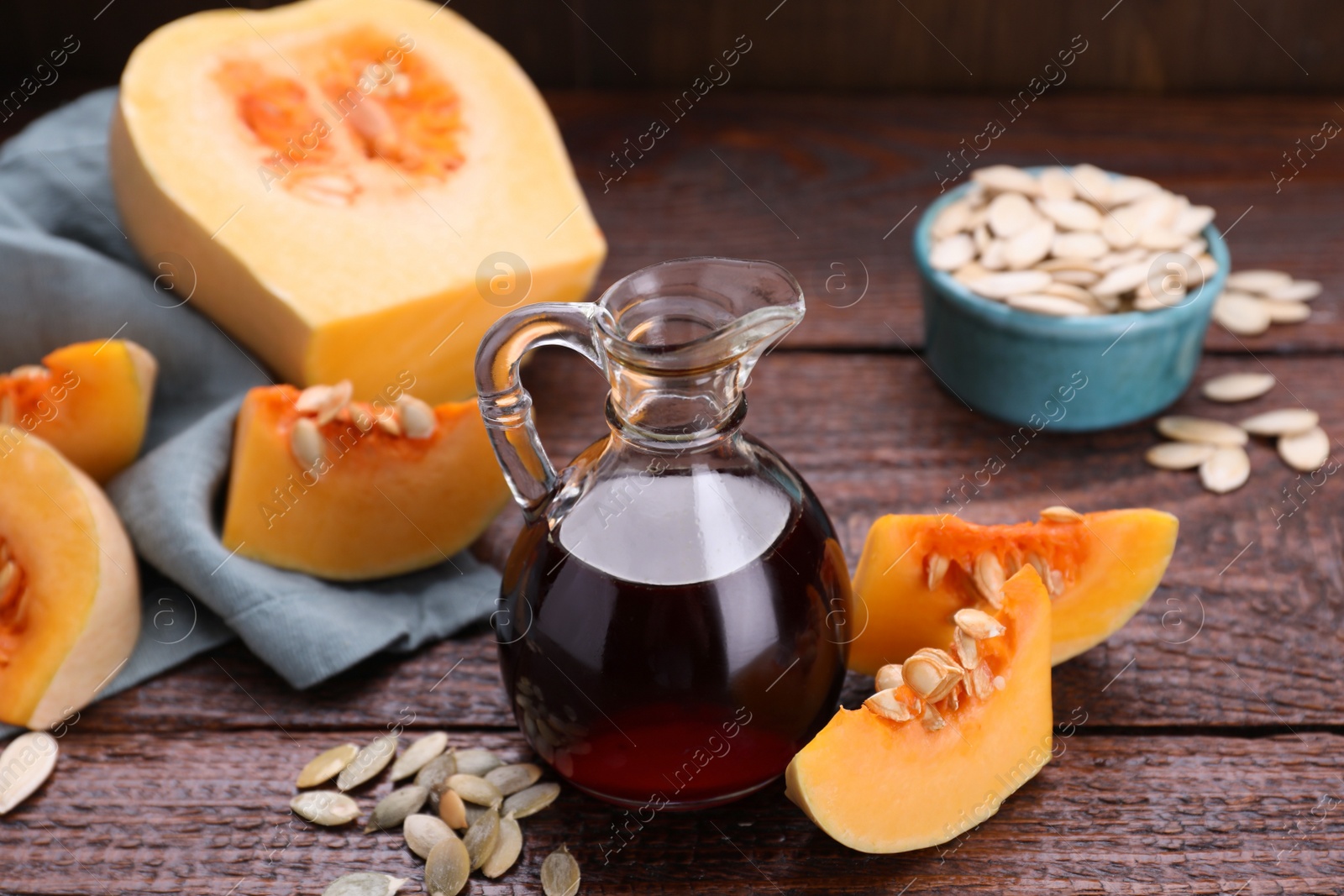 Photo of Fresh pumpkin seed oil in glass jug on wooden table