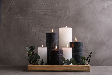 Photo of Tray with burning candles and green branches on table