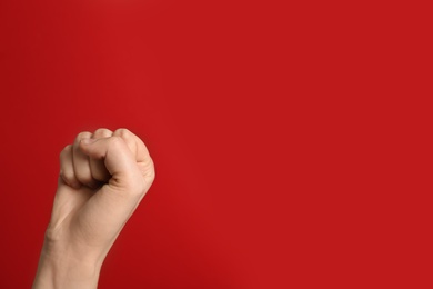 Woman raising her fist and space for text on color background. Victory concept