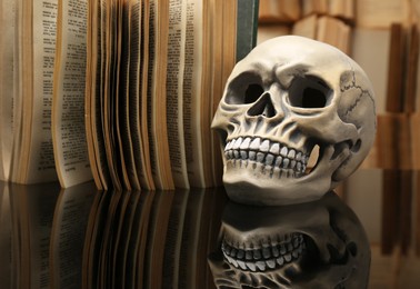 Photo of Human skull and old book on mirror table