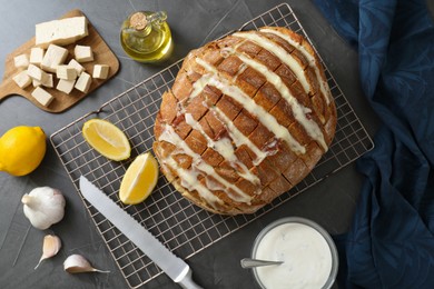 Freshly baked bread with tofu cheese, ingredients and knife on black table, flat lay