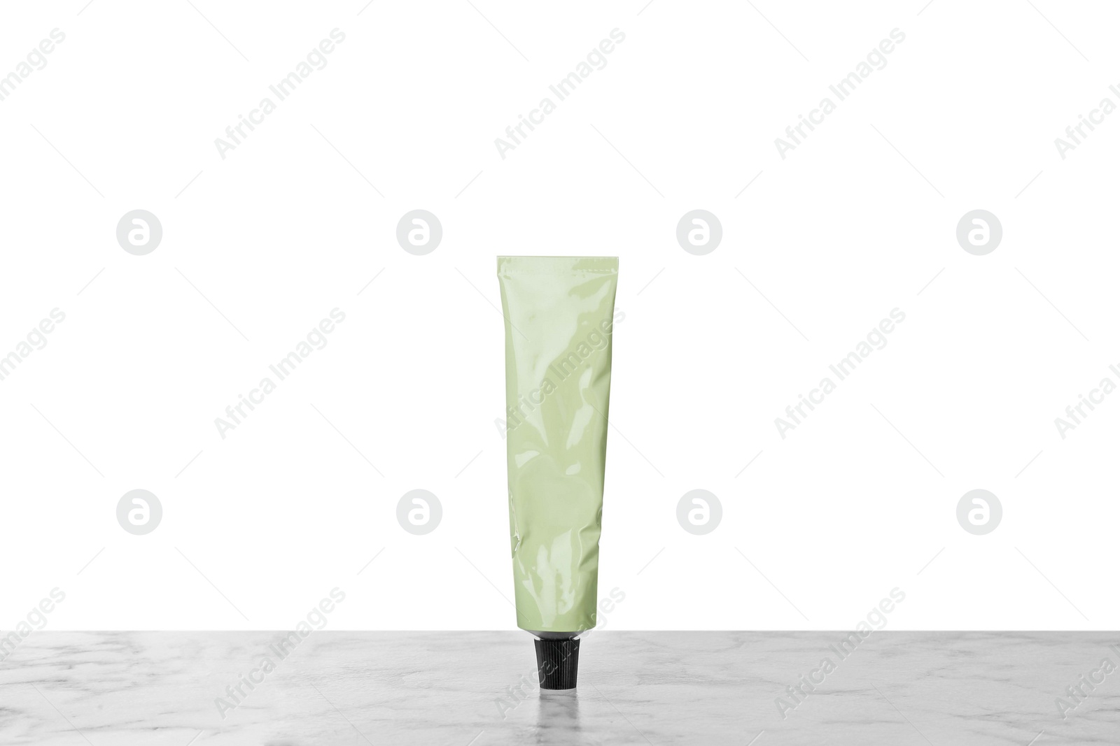 Photo of Tube of hand cream on gray table against white background