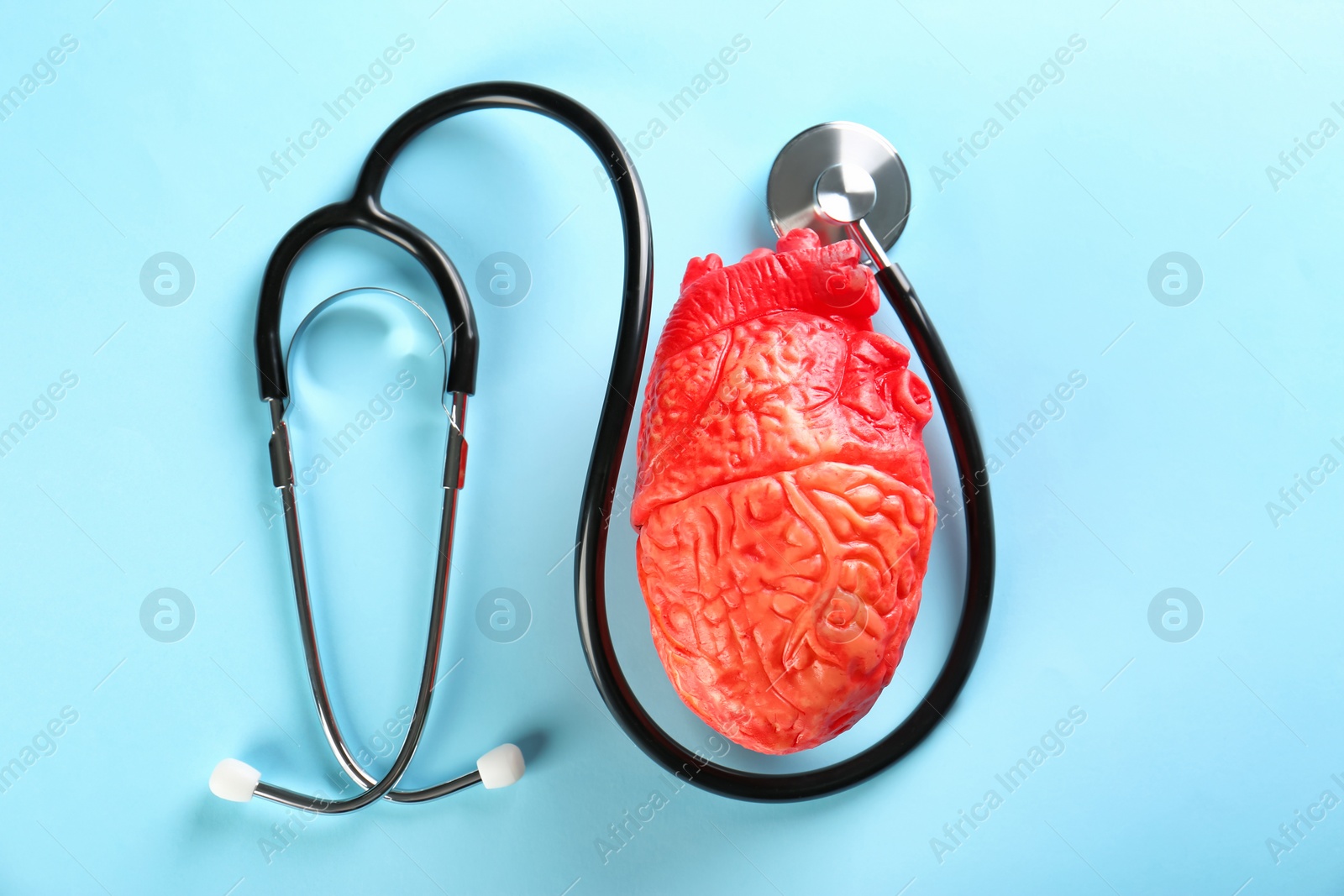 Photo of Stethoscope and model of heart on color background. Heart attack concept