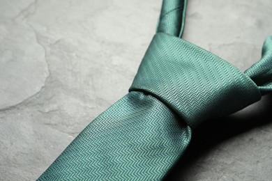 Photo of One green necktie on grey textured table, closeup. Space for text