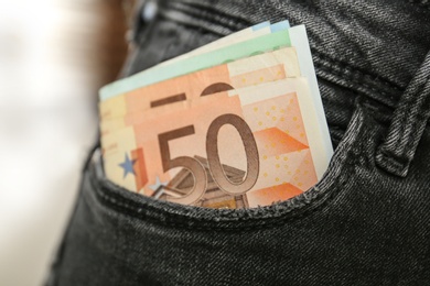 Person with Euro banknotes in pocket of jeans, closeup