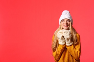 Portrait of emotional young woman in stylish clothes with cup on color background, space for text. Winter atmosphere