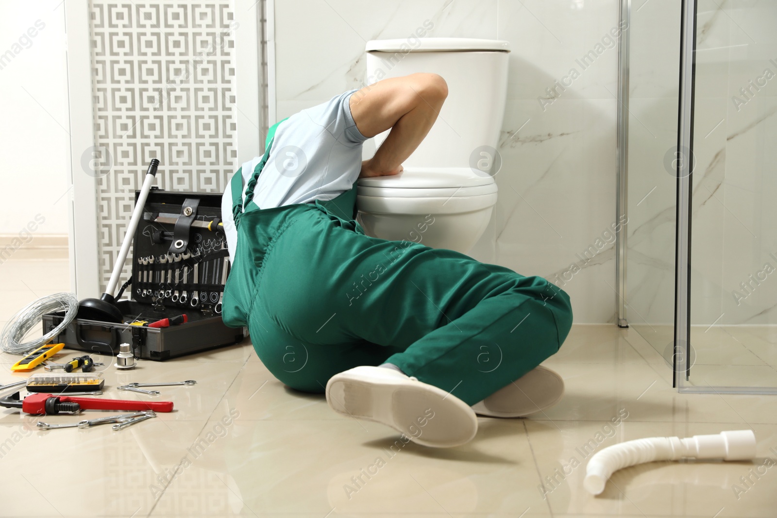 Photo of Professional plumber repairing toilet bowl in bathroom