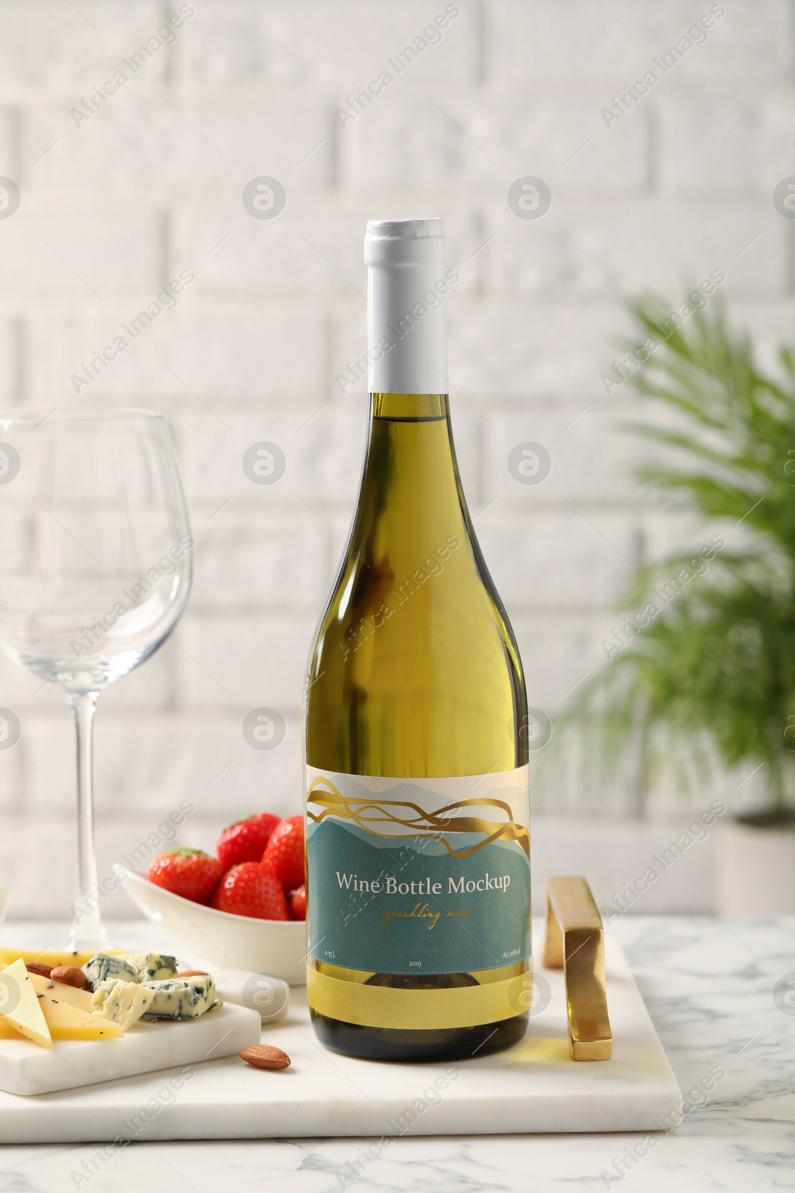 Photo of Bottle of wine, glass and delicious snacks on white marble table