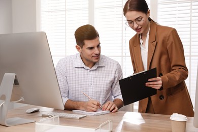 Businesswoman helping intern with work in office