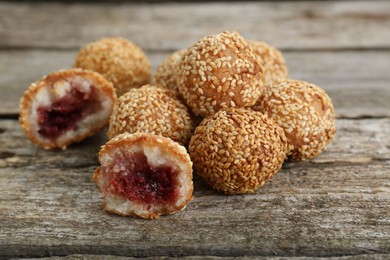 Delicious sesame balls with red bean paste on wooden table, closeup