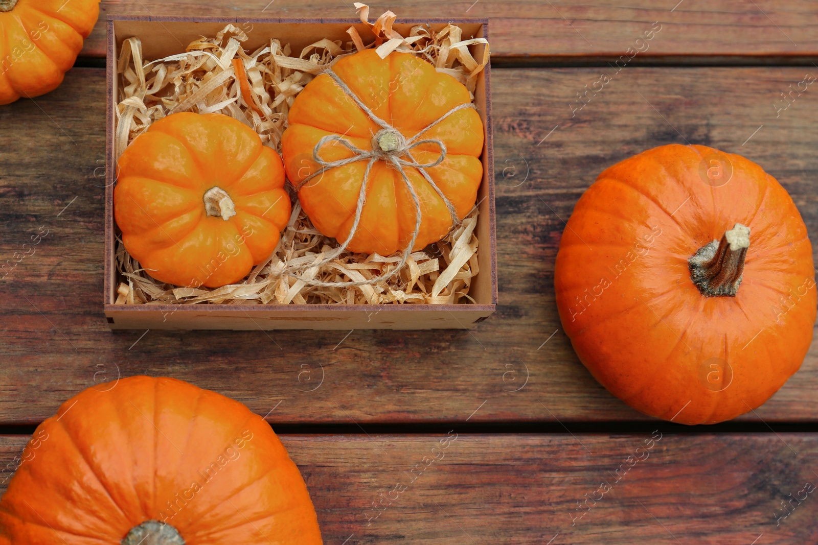 Photo of Crate and ripe pumpkins on wooden table, flat lay