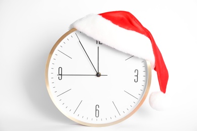 Clock with Santa hat showing five minutes until midnight on white background. New Year countdown