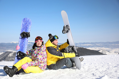 Photo of Couple with snowboards on hill. Winter vacation