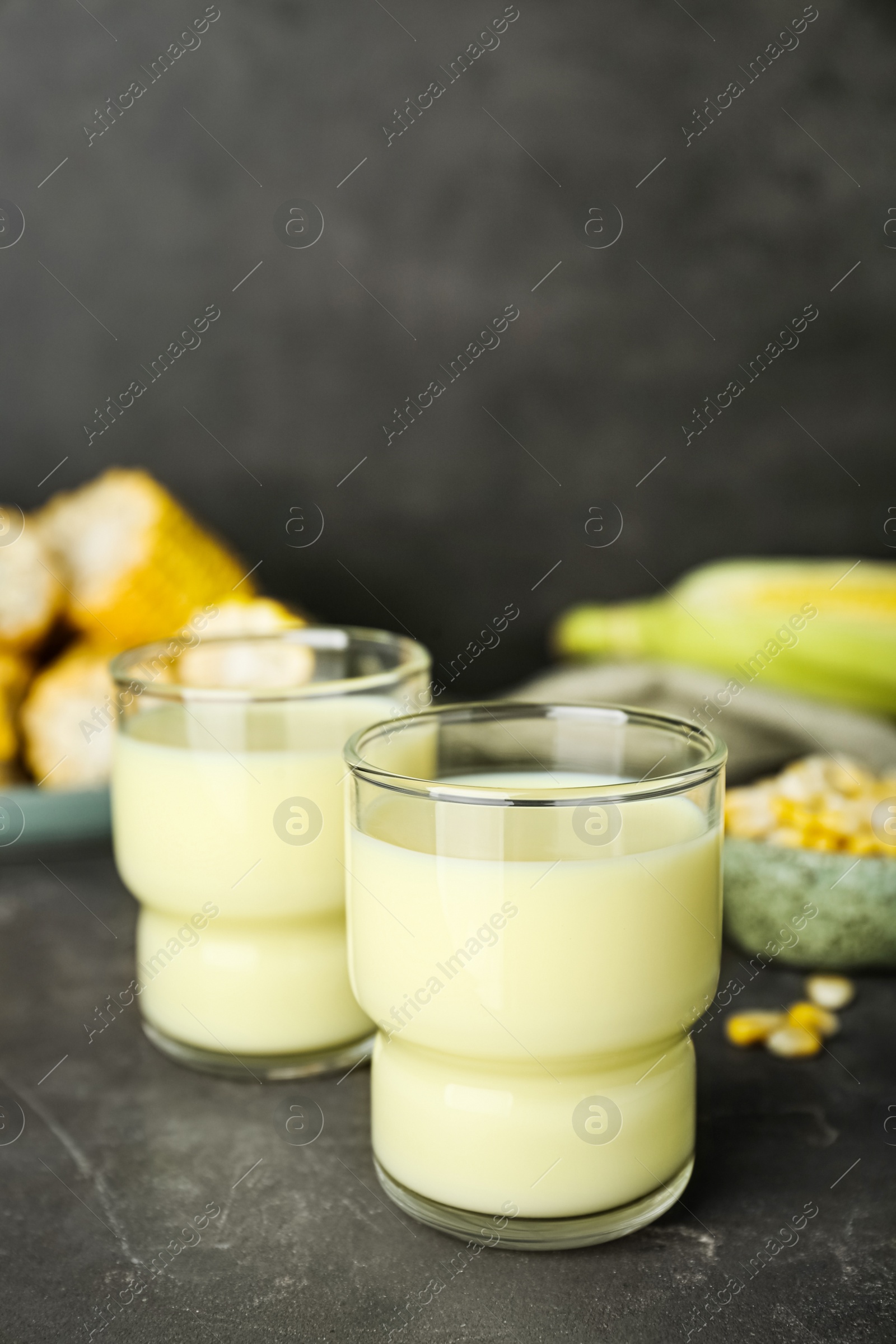 Photo of Tasty fresh corn milk in glass on grey table