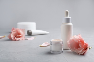 Photo of Jar with hand cream, bottle and flower on table