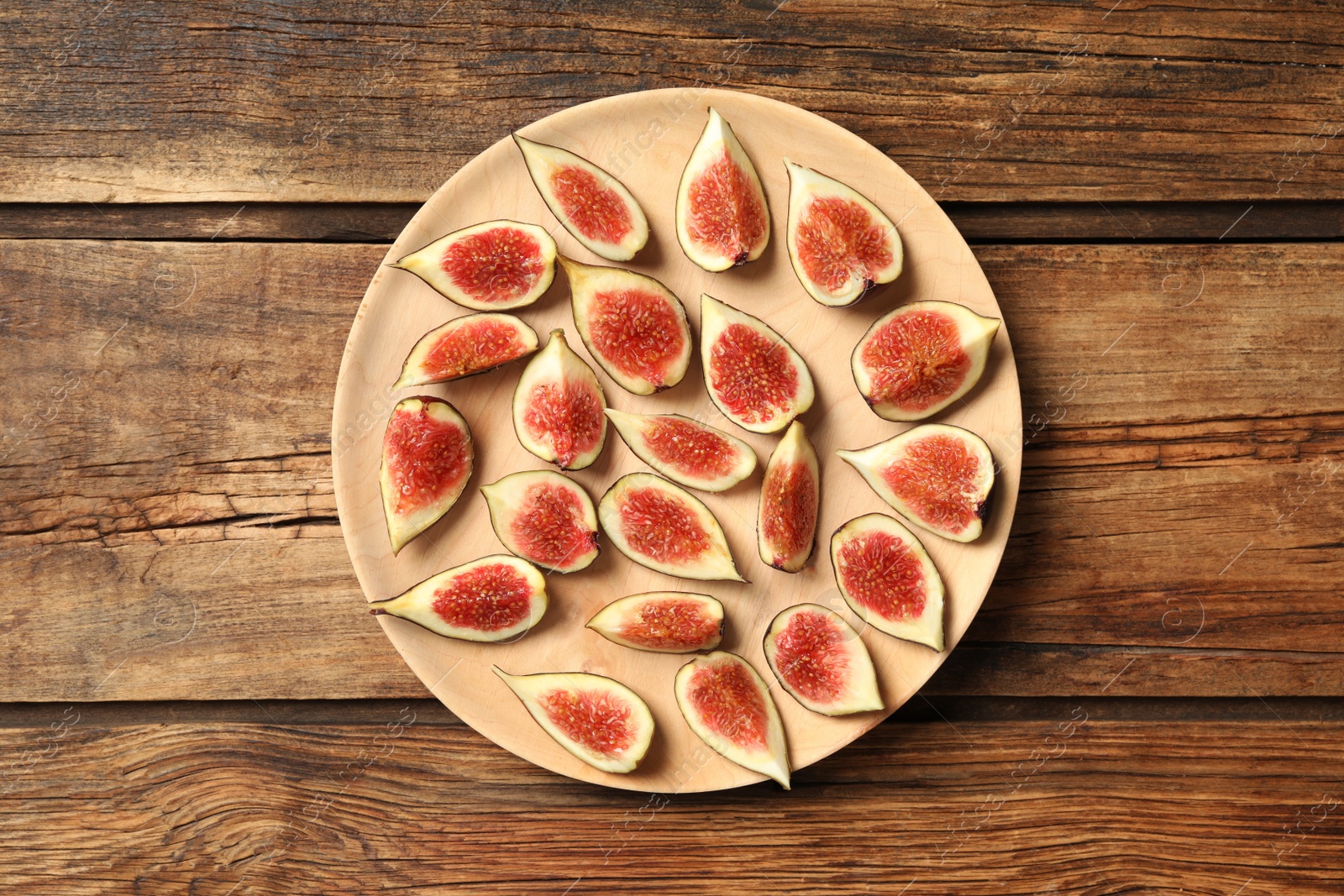 Photo of Slices of tasty fresh figs on wooden table, top view