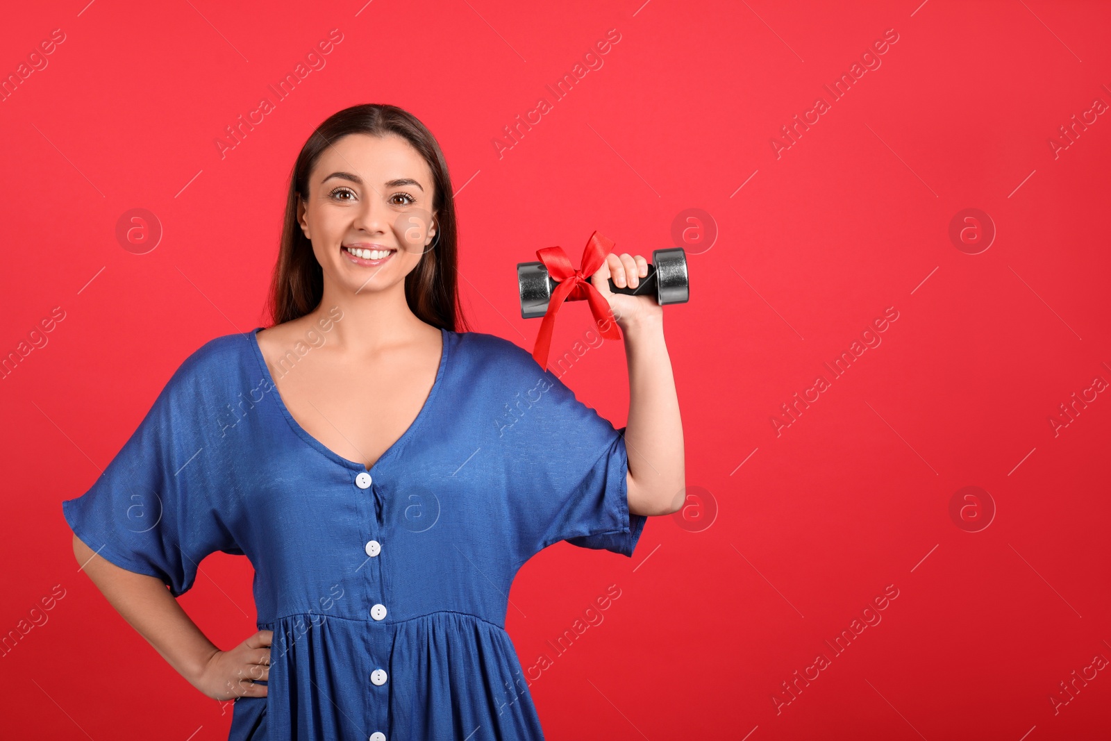 Photo of Woman with dumbbell as symbol of girl power on red background, space for text. 8 March concept