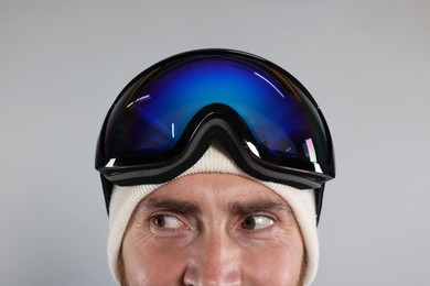 Photo of Winter sports. Man in ski goggles on gray background, closeup