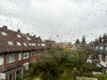 View on city street through window with water droplets on rainy day, closeup