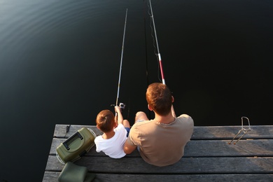 Photo of Dad and son fishing together at lake, above view