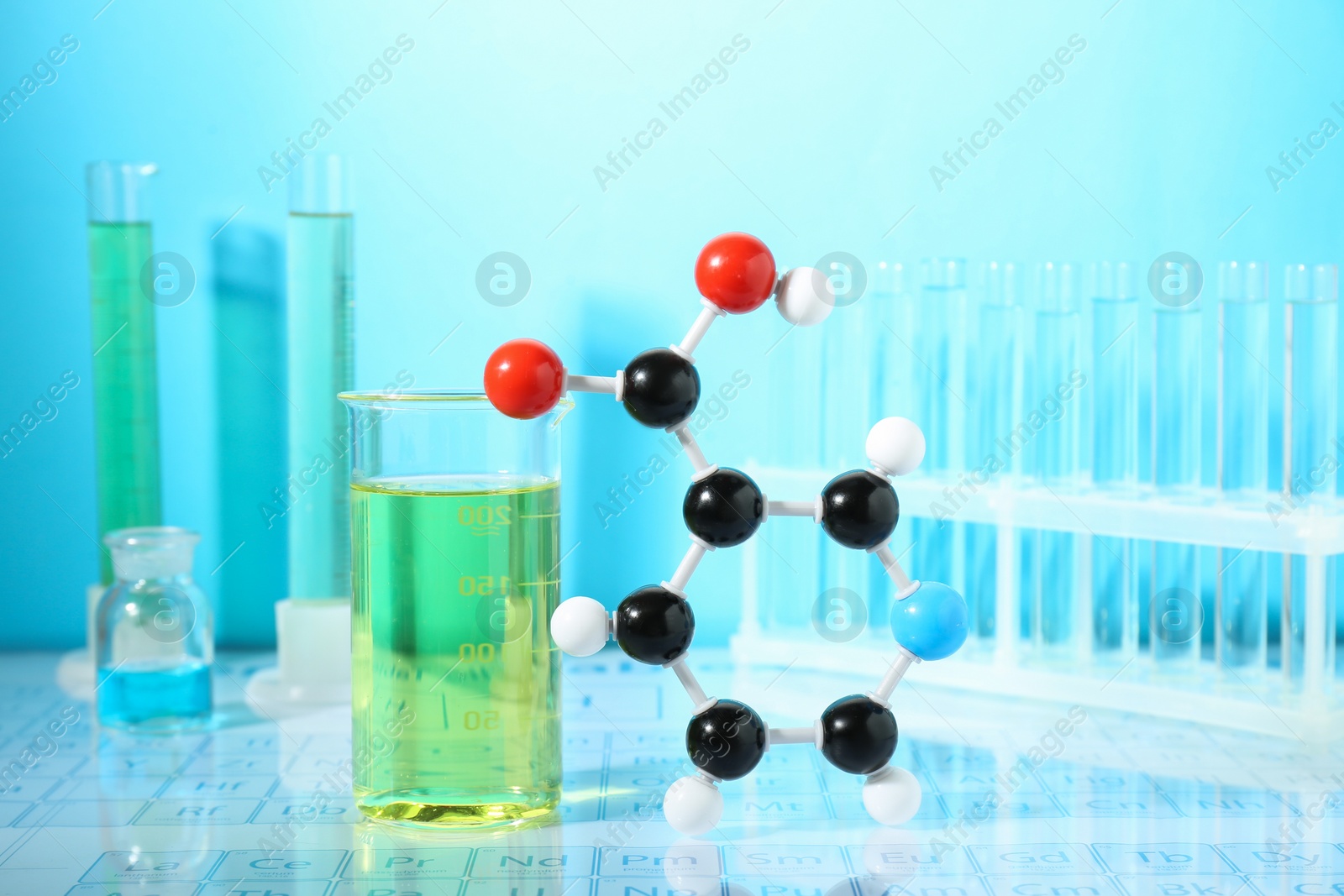 Photo of Molecular model and laboratory glassware against light blue background