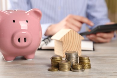 Savings for house purchase. Woman calculating money at wooden table, focus on coins