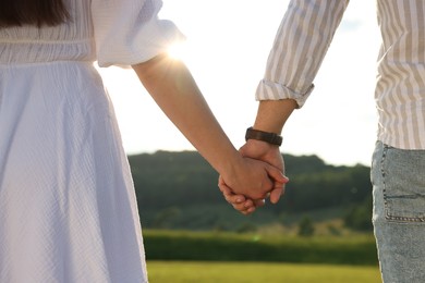 Photo of Romantic date. Couple holding hands outdoors, closeup