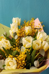 Photo of Bouquet of beautiful spring flowers near turquoise wooden wall, closeup