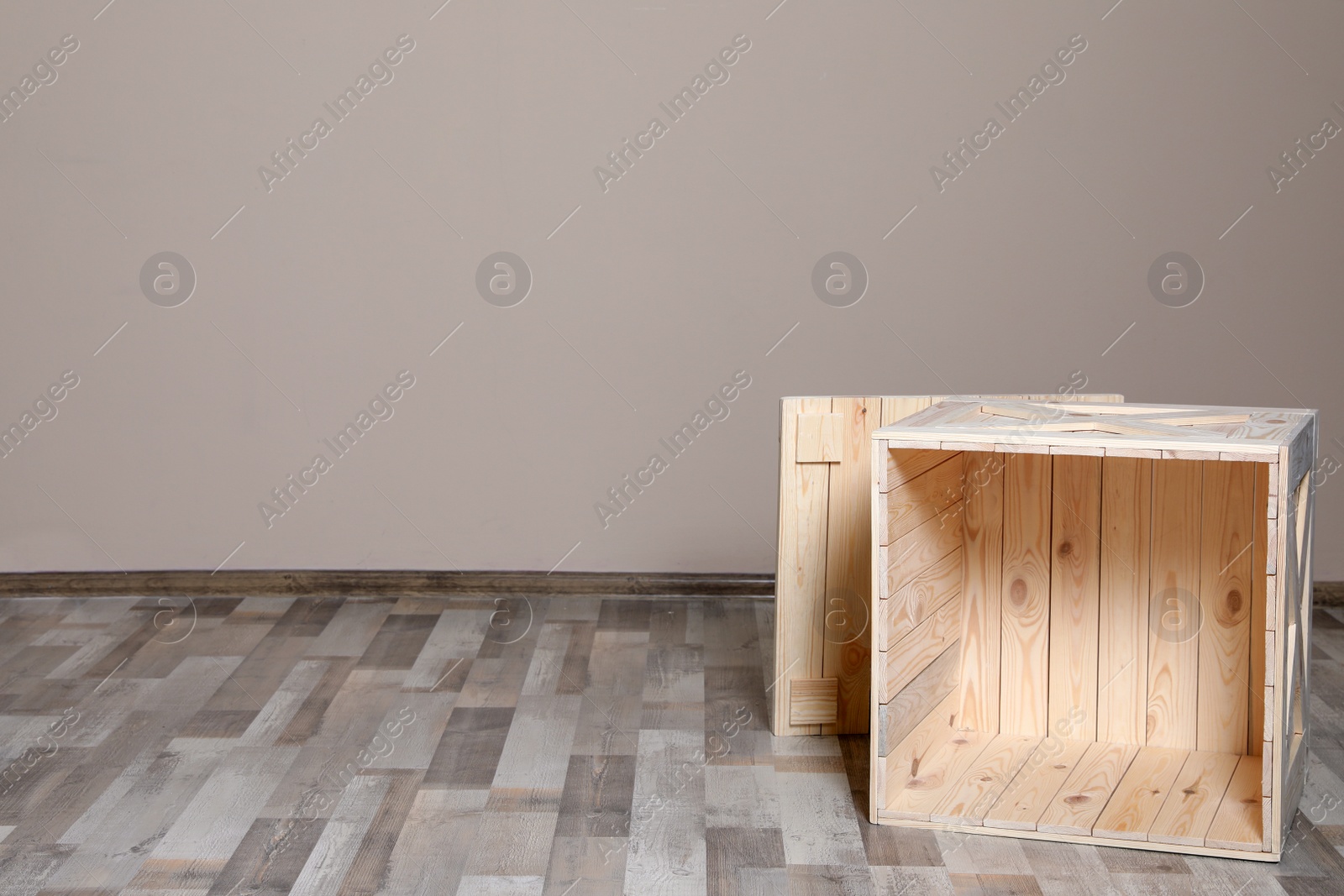 Photo of Wooden crate on floor at beige wall. Space for text