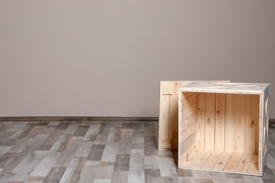 Photo of Wooden crate on floor at beige wall. Space for text