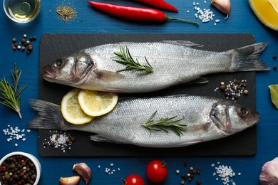 Photo of Flat lay composition with tasty sea bass fish and ingredients on blue wooden table