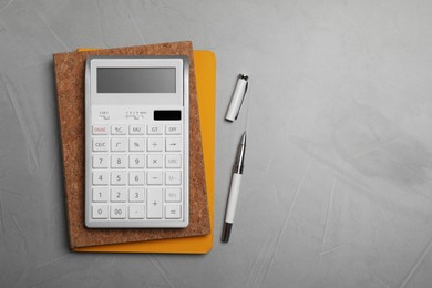 Photo of Calculator and office stationery on grey table, top view. Space for text