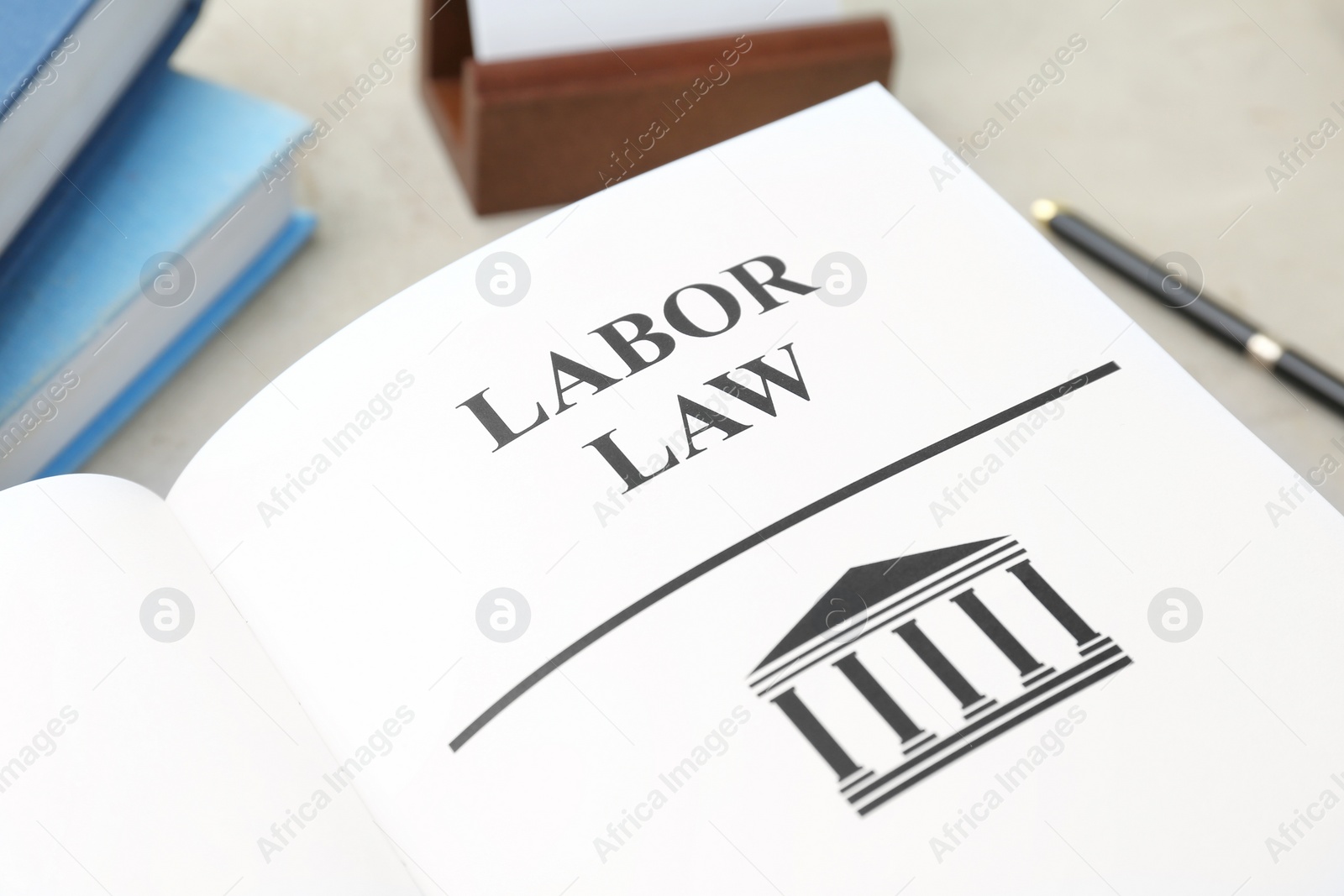 Photo of Open book with words LABOR LAW on table, closeup