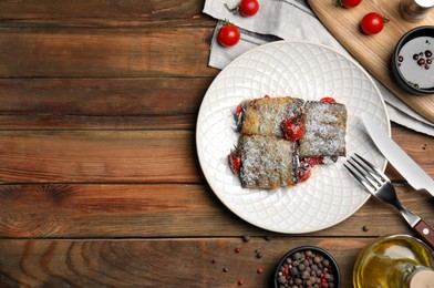Photo of Delicious baked eggplant rolls served on wooden table, flat lay. Space for text