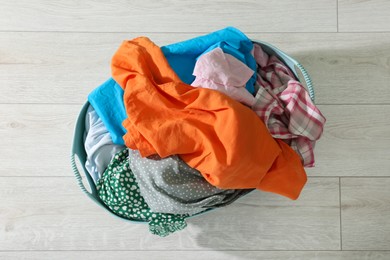 Photo of Laundry basket with clothes on white floor, top view