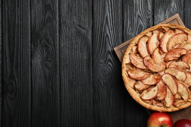 Photo of Delicious apple pie and fresh fruits on black wooden table, top view. Space for text