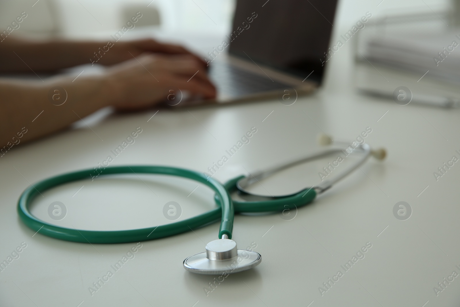 Photo of Doctor at white table in hospital, focus on medical stethoscope