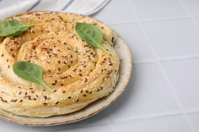 Photo of Delicious puff pastry with spinach on white tiled table, closeup