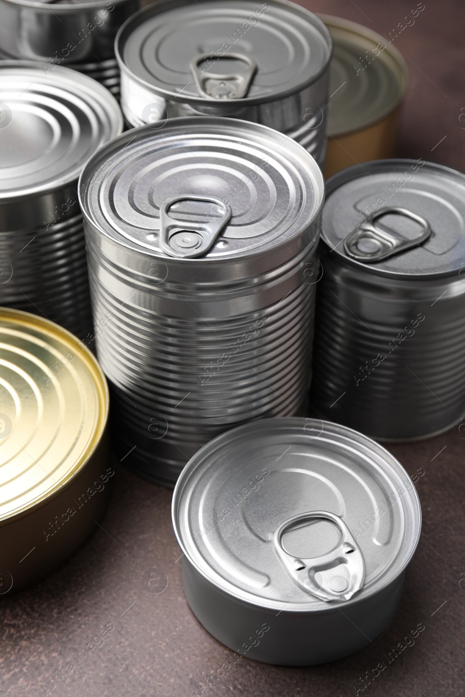 Photo of Many closed tin cans on brown table, closeup