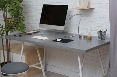 Photo of Interior of comfortable work place with computer on table at home