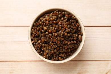 Delicious lentils in bowl on wooden table, top view