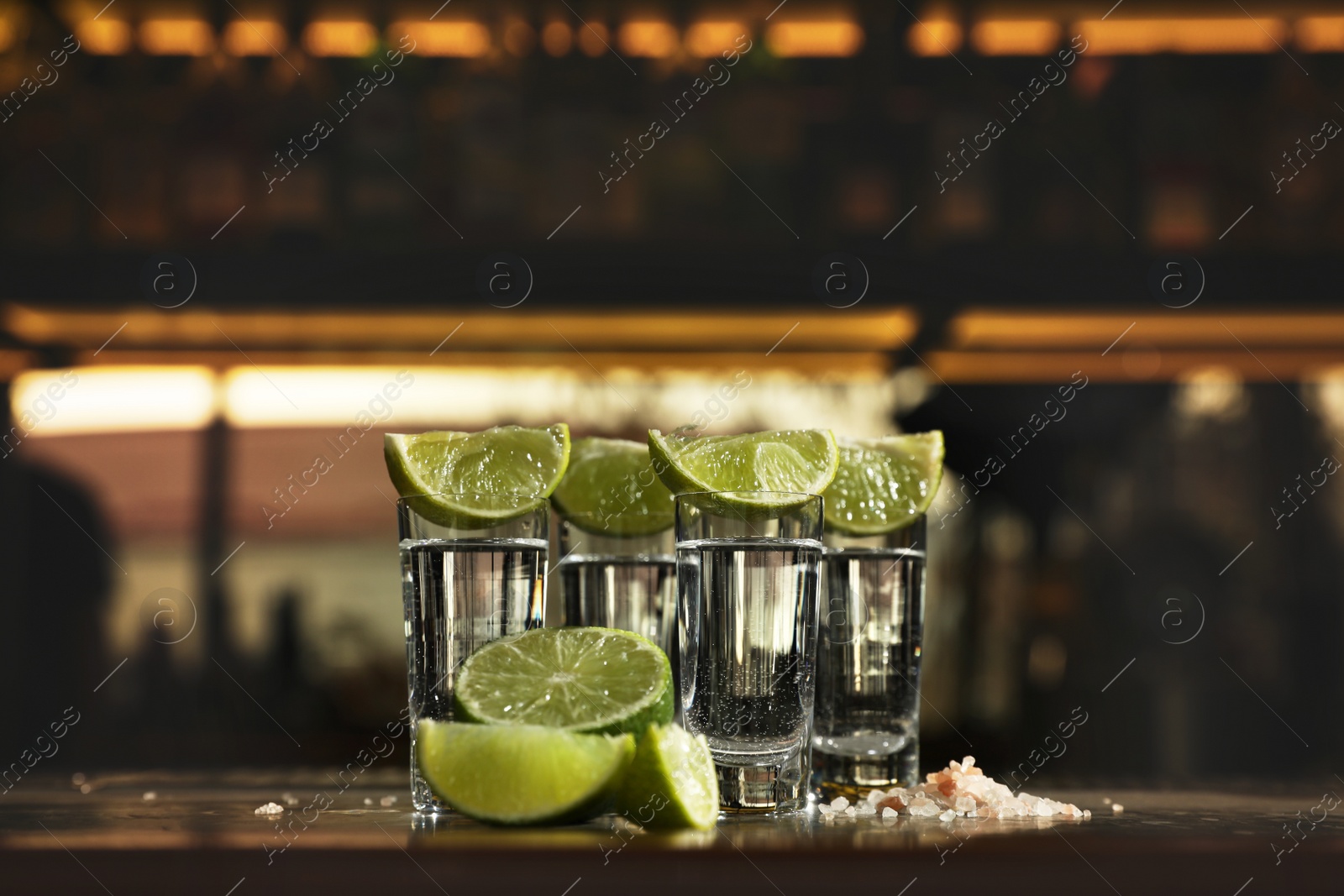 Photo of Mexican Tequila shots, lime slices and salt on bar counter