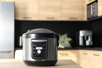 Modern multi cooker on table in kitchen, space for text