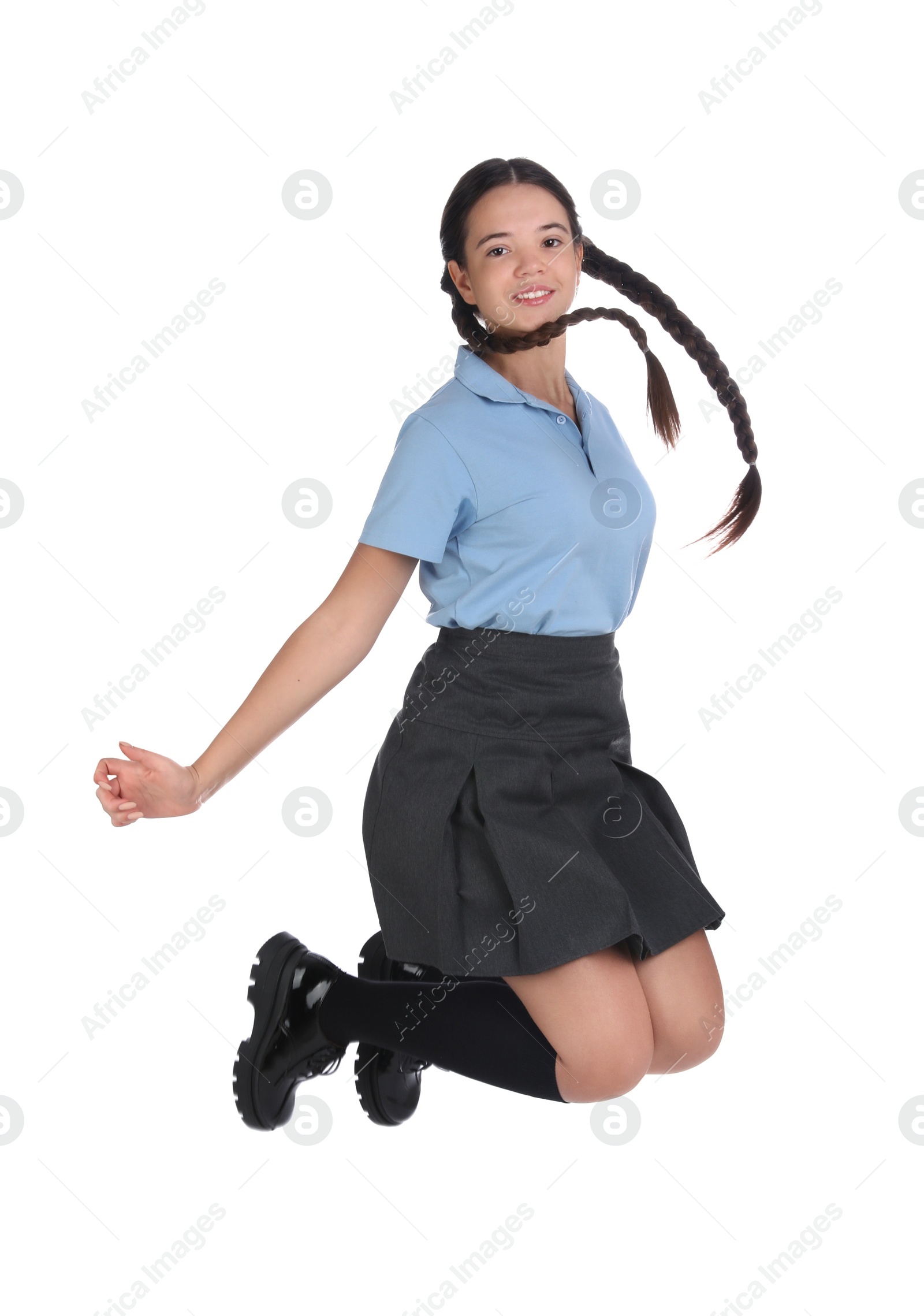 Photo of Teenage girl in school uniform jumping on white background