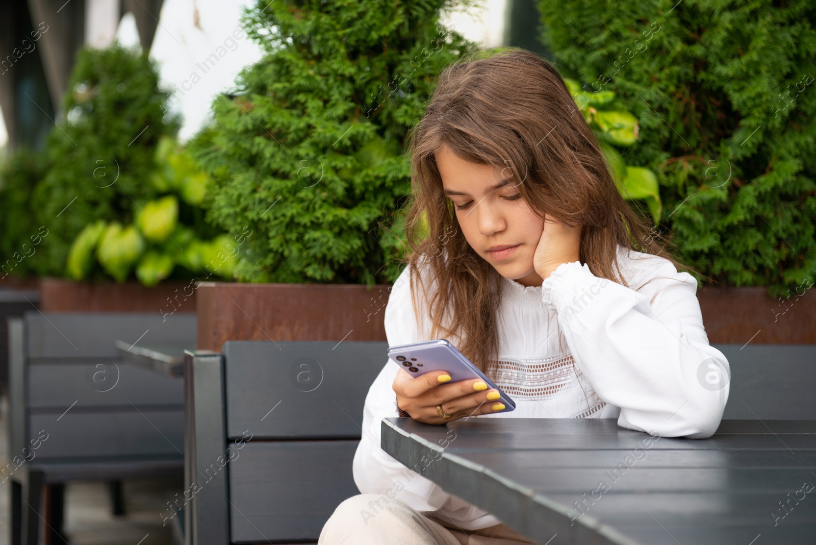 Photo of Teenage girl using smartphone at table in outdoor cafe, space for text