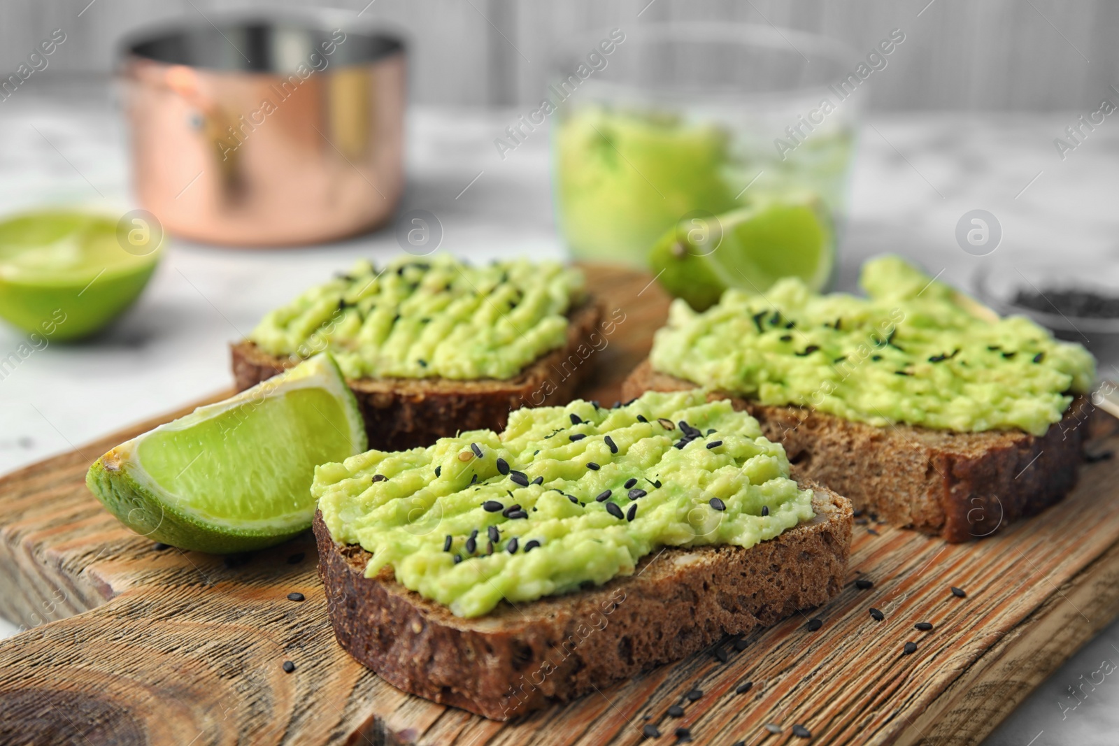 Photo of Crisp rye toasts with avocado on wooden board, closeup