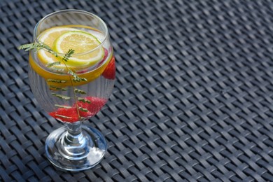 Photo of Delicious refreshing lemonade with raspberries on black rattan surface, space for text
