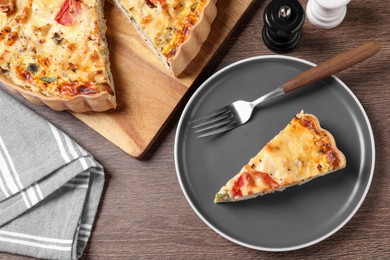 Tasty quiche with tomatoes and cheese served on wooden table, flat lay